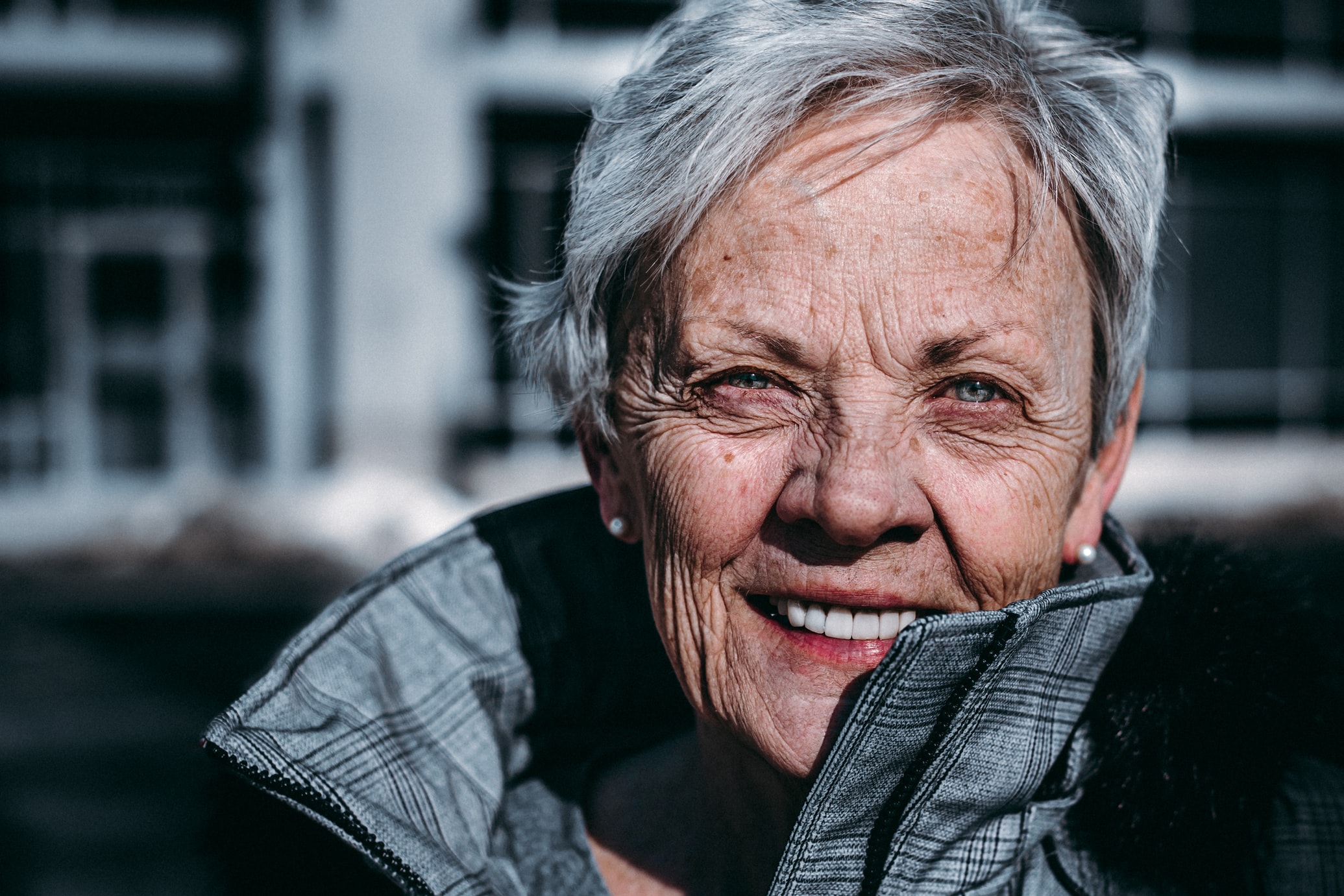 Glad äldre kvinna utomhus med ytterkläder och vind i håret
