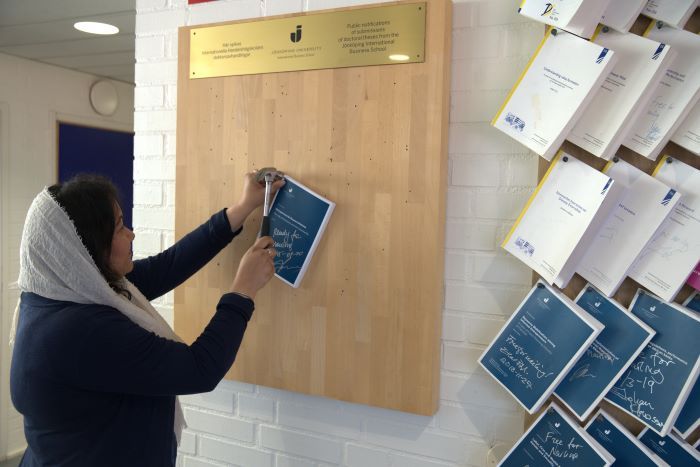 Woman nailing thesis to a wall