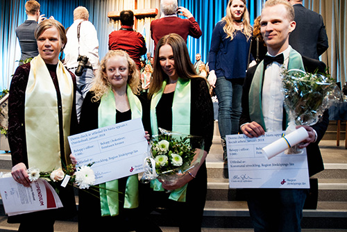 Fyra studenter som tagit emot diplom och blommor