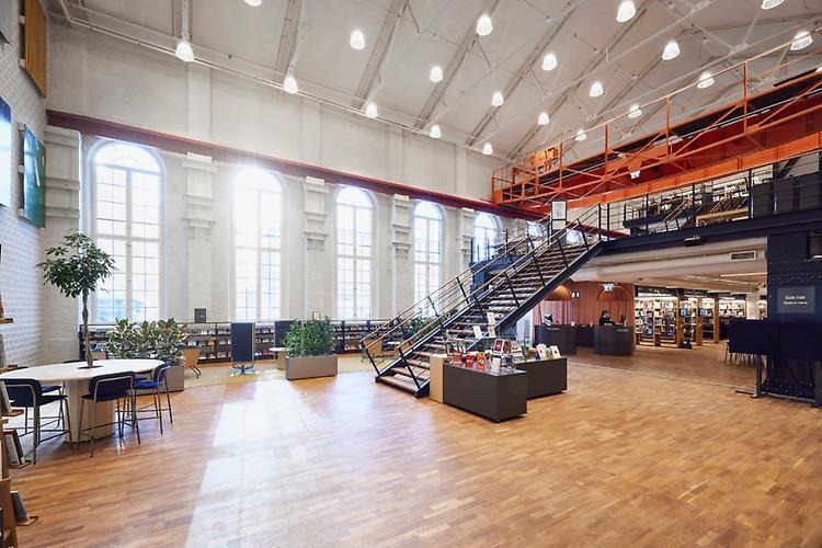 The entrance area of the library, with a big staircase and the sun shining through big windows.
