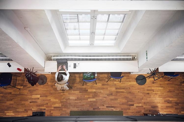 A photo from above, where you can see a student sitting by a table below a big window.