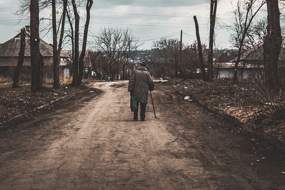 Äldre man går ensam i en ukrainsk by