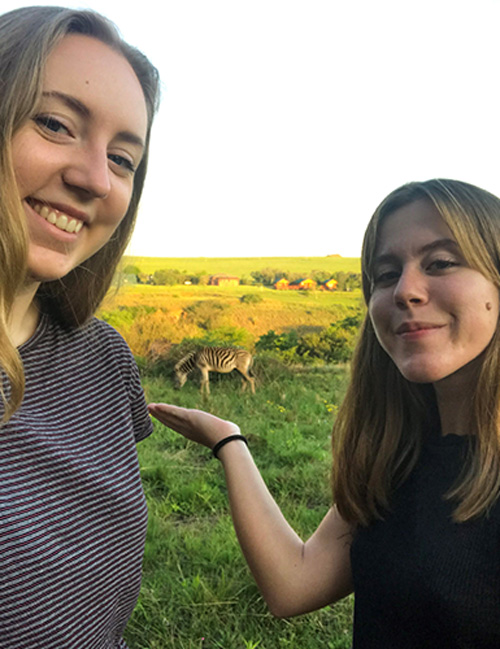 Sofia Irewall och Elina Hübsch i Sydafrika med en zebra i bakgrunden
