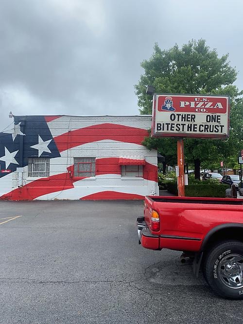Röd pick up bild framför ett hus med amerikanska flaggan målad på fasaden