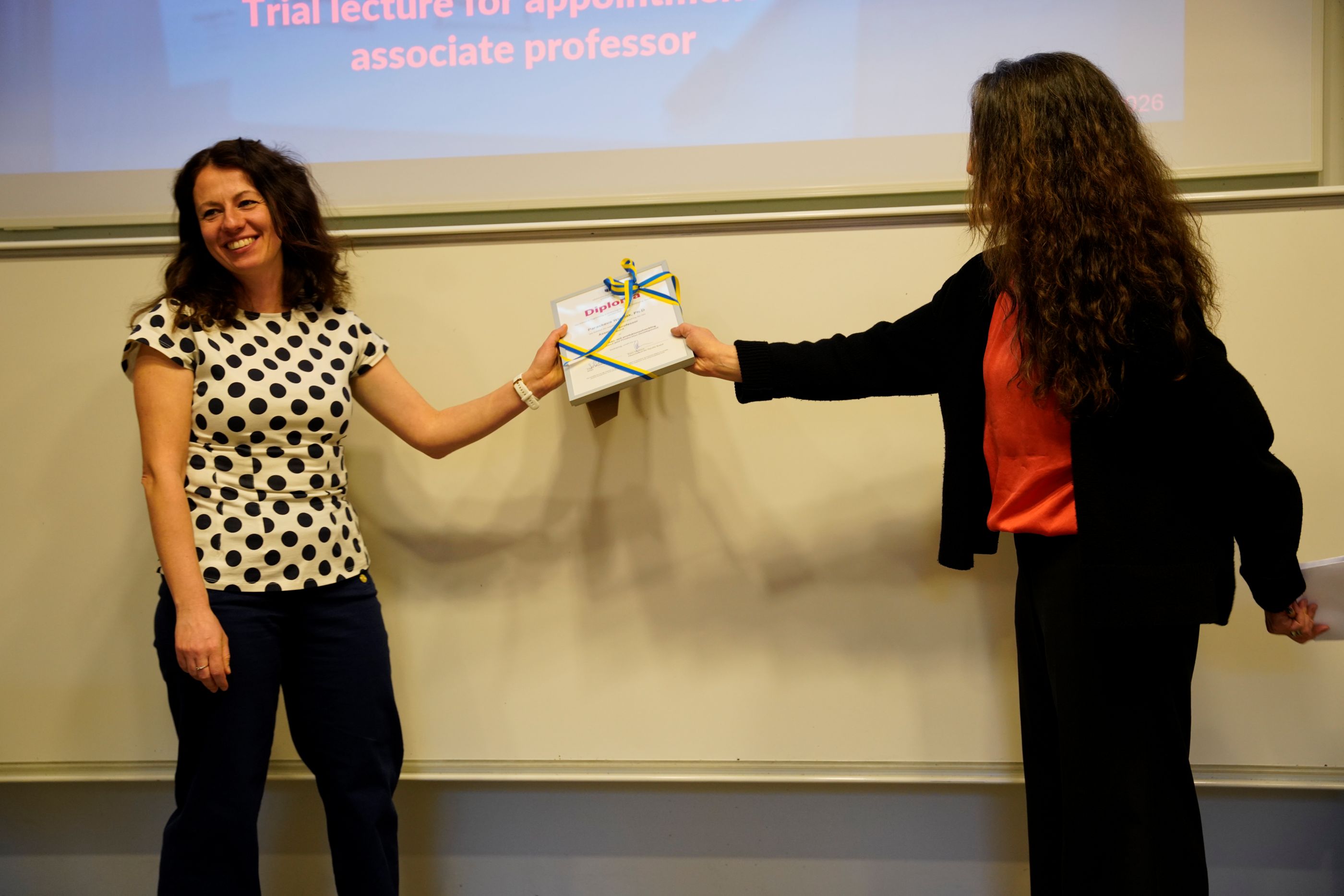 Smiling woman receiving a diploma.
