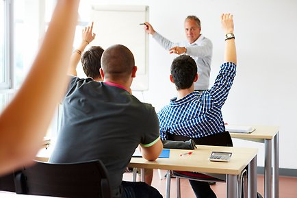 Student som räcker upp handen i ett klassrum